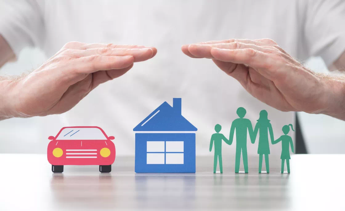 dłonie nad ilustracją domu rodziny i samochodu